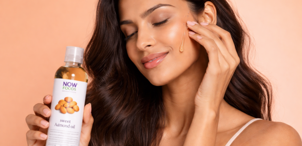Woman applying NOW Foods sweet almond oil on glowing skin
